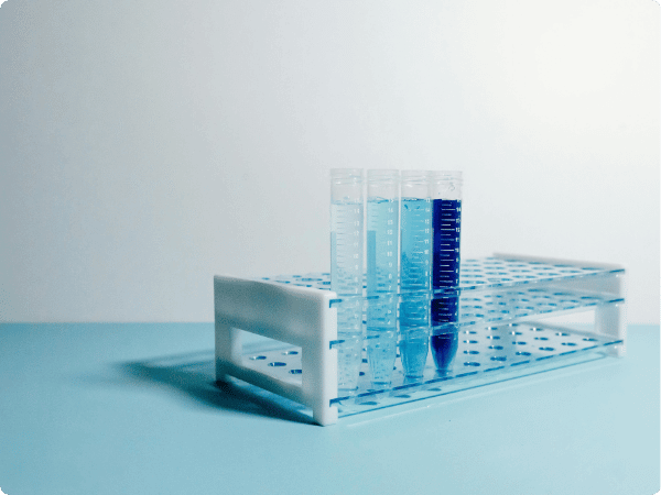 Four test tubes filled with blue liquid sitting on top of a blue table in Portabull Cold Storage container- NEW